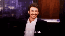 a man in a suit and white shirt is smiling and says `` i 'm a nerd '' .