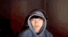 a young man wearing a blue hoodie and headphones is sitting in a dark room .