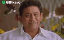 a man in a white shirt is smiling and making a face .