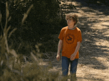 a young boy wearing an orange t-shirt with a deer on it