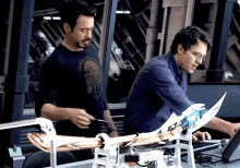 a man in a blue shirt is standing next to another man in a blue shirt