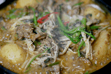 a close up of a stew with noodles and meat