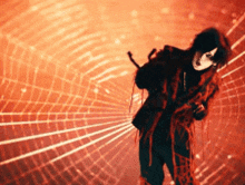 a person in a red and black outfit stands in front of a red background