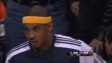 a man wearing a yellow headband sits in the stands during a basketball game