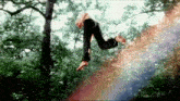 a person is jumping in the air with a rainbow behind them .