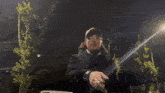 a man with long hair is wearing a hat and sunglasses while standing in the dark .
