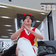 a man in a red and white outfit is sitting on a couch in front of a scoreboard