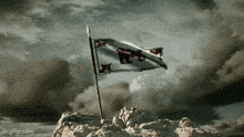 a flag on top of a hill with a cloudy sky behind it