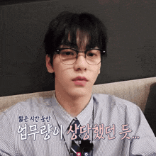 a man wearing glasses and a striped shirt with foreign writing on the bottom