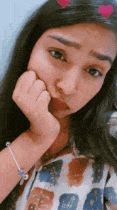 a girl with a bracelet on her wrist has her hand on her face