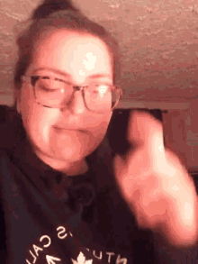 a woman wearing glasses and a black shirt is making a funny face .