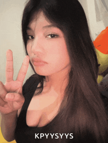 a woman giving a peace sign with the letters kpyysyys behind her