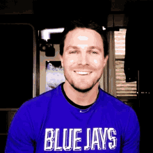 a man is wearing a blue jays shirt and smiling