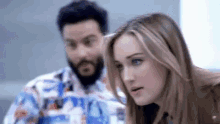 a man and a woman are sitting next to each other looking at a computer screen .