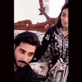 a man and woman are sitting on a couch and the man is looking at the woman
