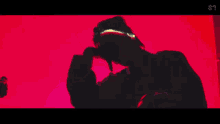 a close up of a person holding a pink object in a red room with neon lights .