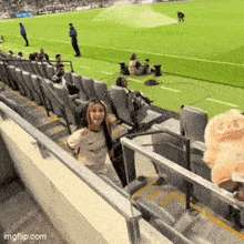 a girl is standing in the stands of a soccer stadium with a stuffed animal that says pig on it