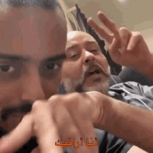 a man with a mustache is giving the peace sign