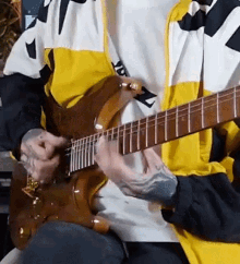 a man in a yellow and white jacket is playing a guitar