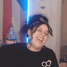 a woman wearing a bandana and a black shirt with the number 8 on it laughs
