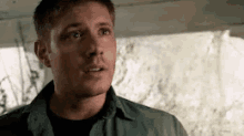 a man in a green shirt is looking at the camera .