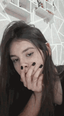 a girl with black nails is covering her face with her hand