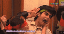 a man with a green headband is being held by a woman with blindfolds