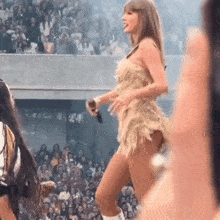 a woman in a short dress is standing on a stage in front of a crowd holding a microphone .
