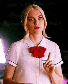 a woman wearing a white shirt and a red bow tie is pointing up .
