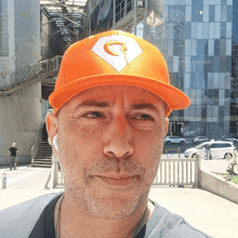 a man wearing an orange hat with the letter g on it stands in front of a building