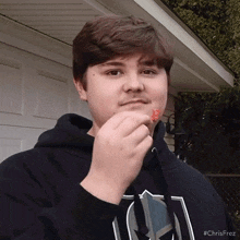 a young man wearing a black hoodie is eating something