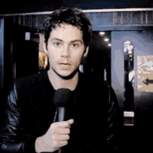 a man in a black jacket holds a microphone in his hand