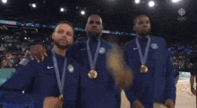 a group of men wearing medals on a basketball court with the olympics logo in the background