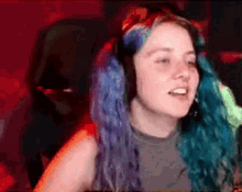 a woman with blue hair is wearing headphones while sitting in a chair .