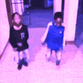 a blurry picture of two people walking down a hallway with one wearing a black shirt with the letter t on it