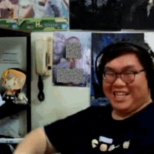 a man wearing headphones and glasses is smiling in front of a wall that has a picture of a man on it