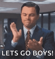 a man in a suit and tie is clapping his hands and saying `` let 's go boys ! ''