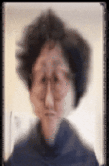 a blurry picture of a woman wearing glasses and a blue sweater