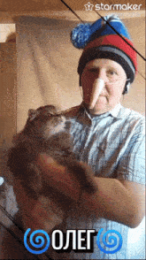 a man wearing a hat and headphones is holding a cat with a starmaker logo on the bottom right