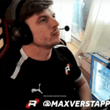 a man wearing headphones and a puma shirt is sitting in front of a computer screen with @maxverstappen written below him