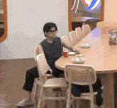 a man is sitting on a chair in front of a long table with plates on it .