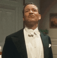 a man in a tuxedo and bow tie looks up at something