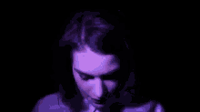 a close up of a woman 's face in a dark room with a purple light coming out of her eyes .