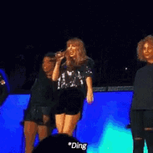 a woman is singing into a microphone while another woman stands behind her and says ding