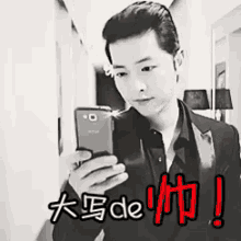 a man in a suit is taking a selfie with a cell phone with chinese writing on it