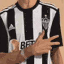 a man is wearing a black and white striped shirt and giving a thumbs up .