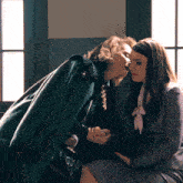 a woman in a green coat talks to another woman