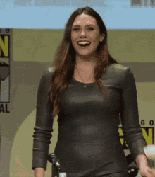 a woman in a leather dress is smiling in front of a sign that says n on it