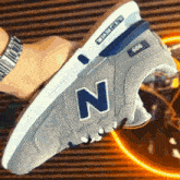 a person wearing a watch and a pair of grey new balance sneakers