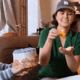 a woman wearing a la hat is holding a cake and a candle .